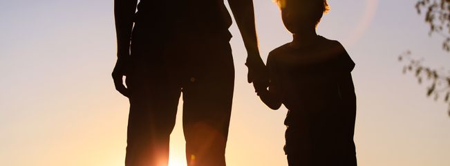 Father and son holding hands at sunset