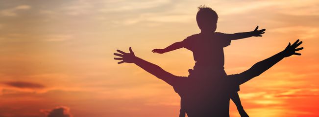 Father with child on shoulders at sunset